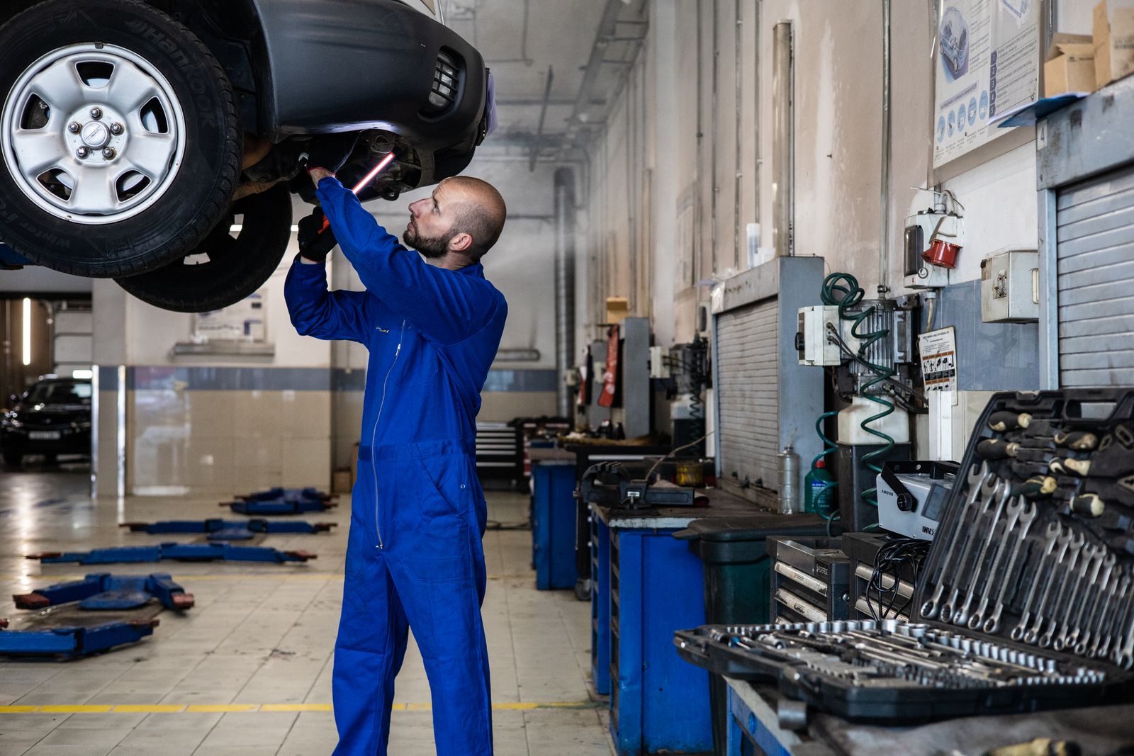 Mechanic inspecting the underside of a car raised on a lift