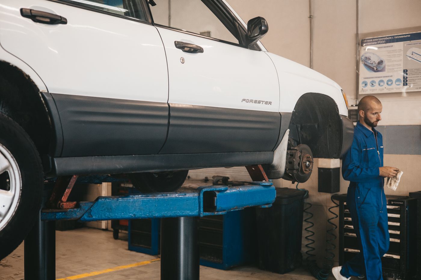 Vehicle on a lift while a mechanic checks it with a clipboard